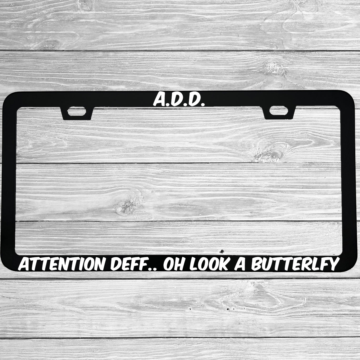 Close-up of "ADD Attention Def Oh Look A Butterfly" license plate frame showing fade-proof print quality