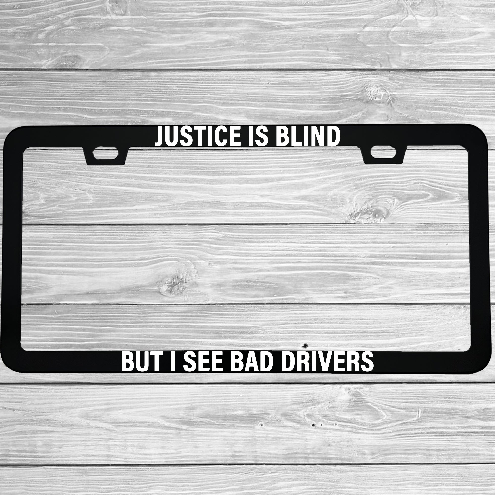 Close-up of "Justice Is Blind, But I See Bad Drivers" license plate frame showing fade-proof print quality