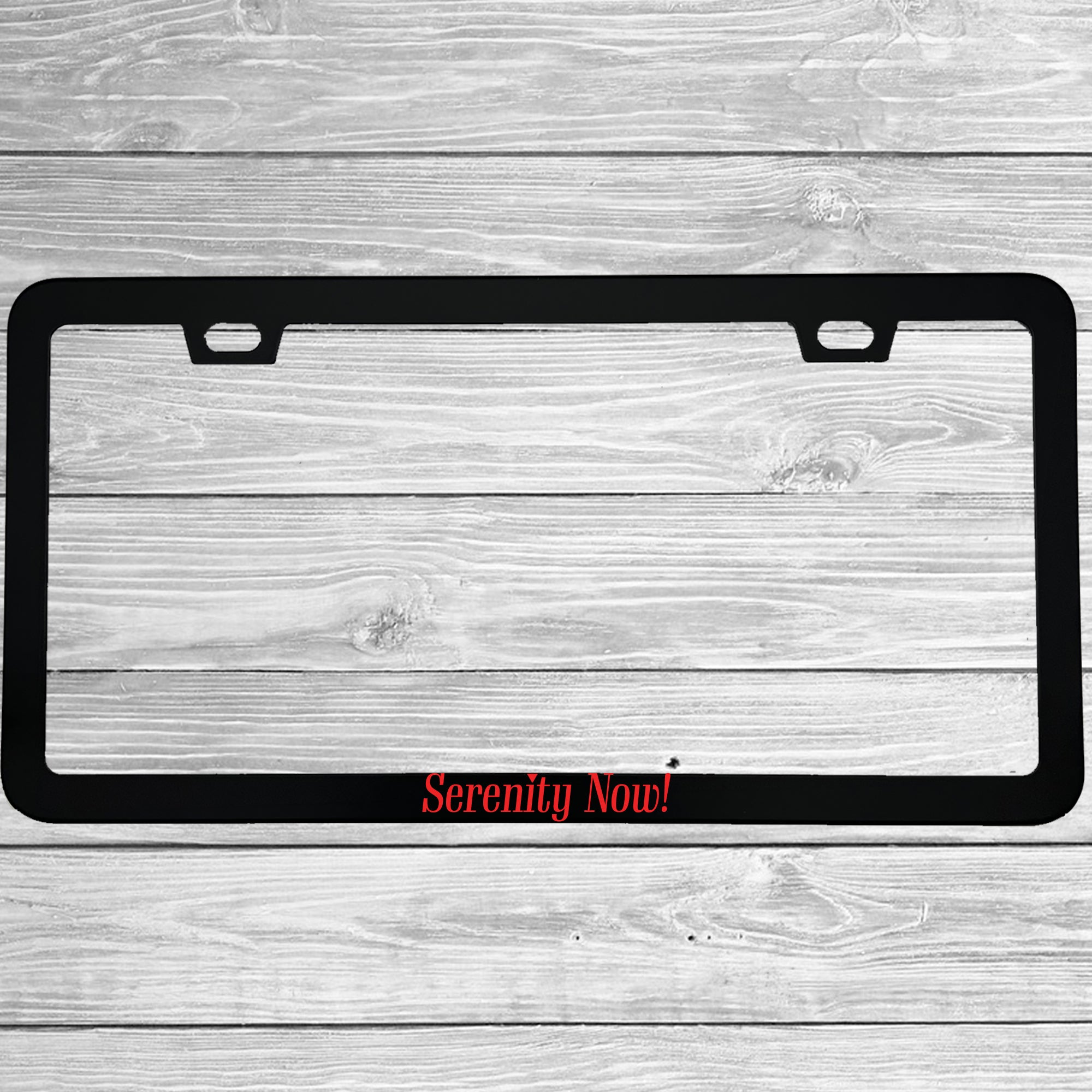 Close-up of "Serenity Now" license plate frame showing fade-proof print quality