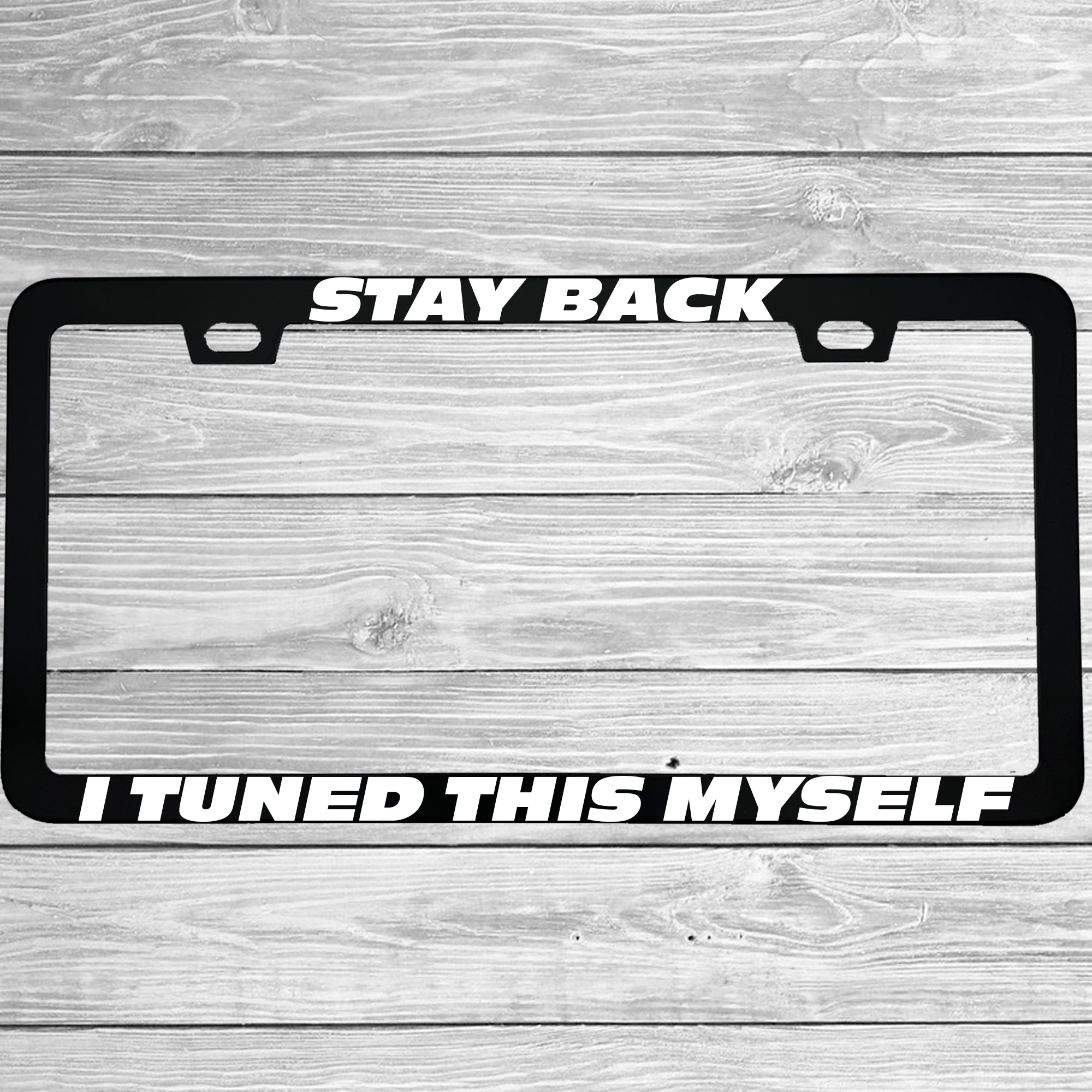 Close-up of "Stay Back I Tuned This Myself" license plate frame showing fade-proof print quality
