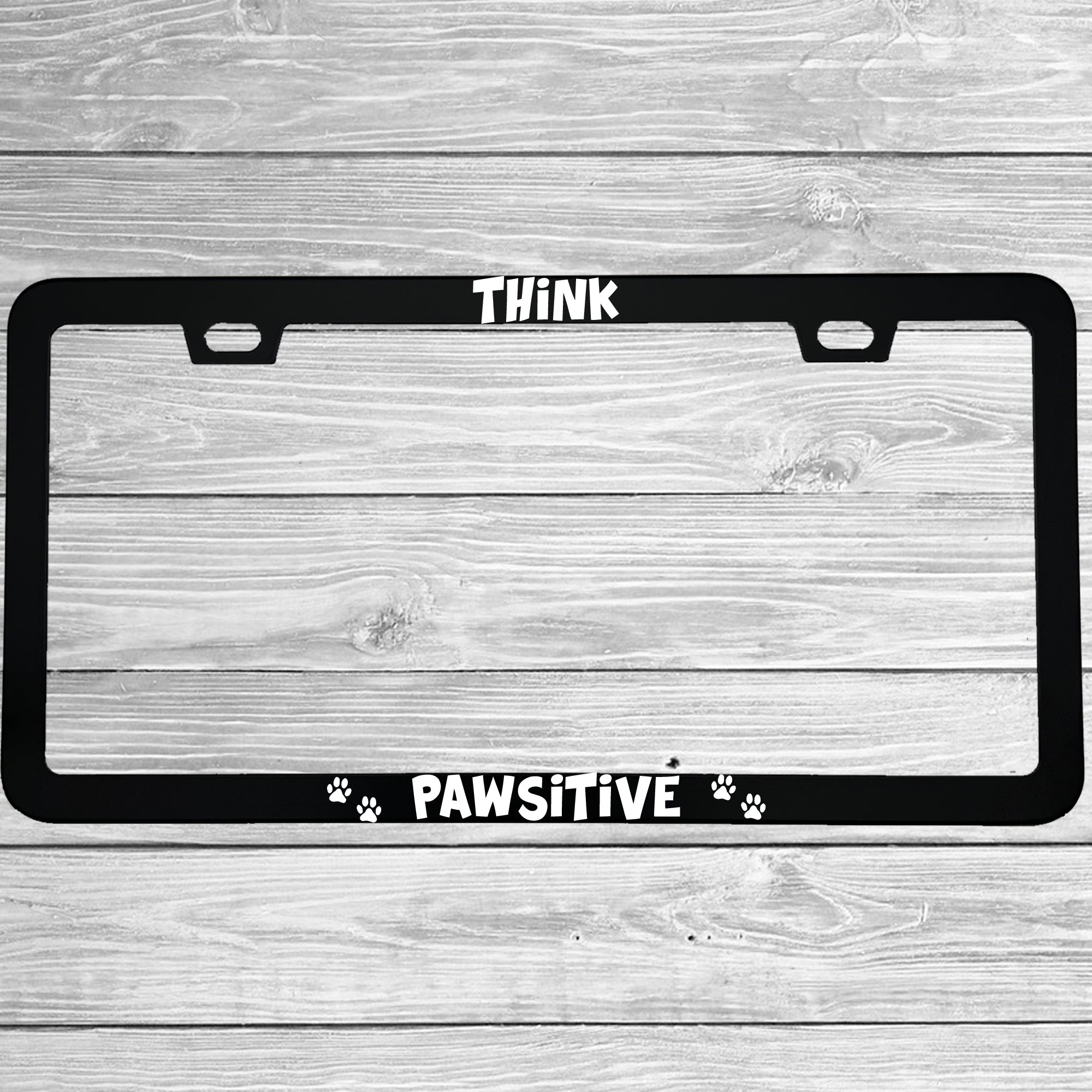 Close-up of "Think Pawsitive (Positive)" license plate frame showing fade-proof print quality