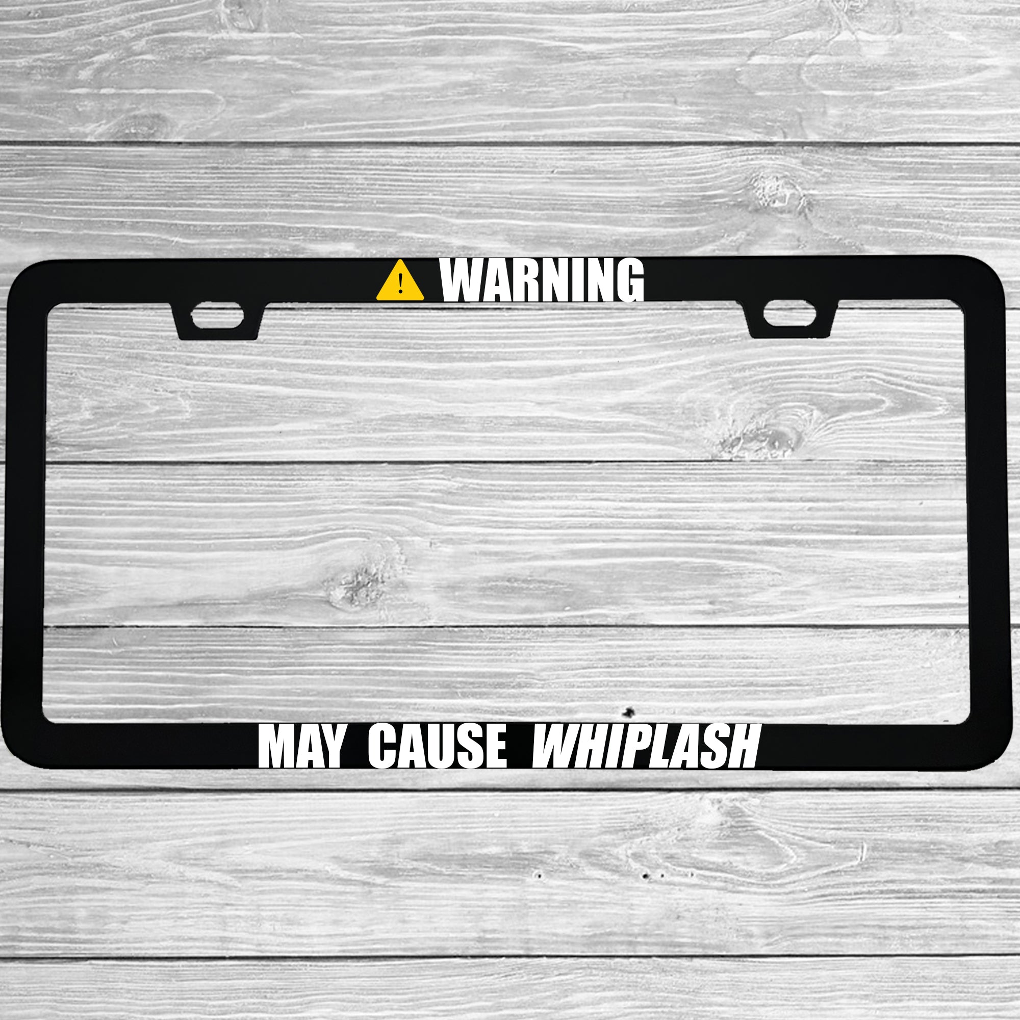 Close-up of "Warning: May Cause Whiplash" license plate frame showing fade-proof print quality