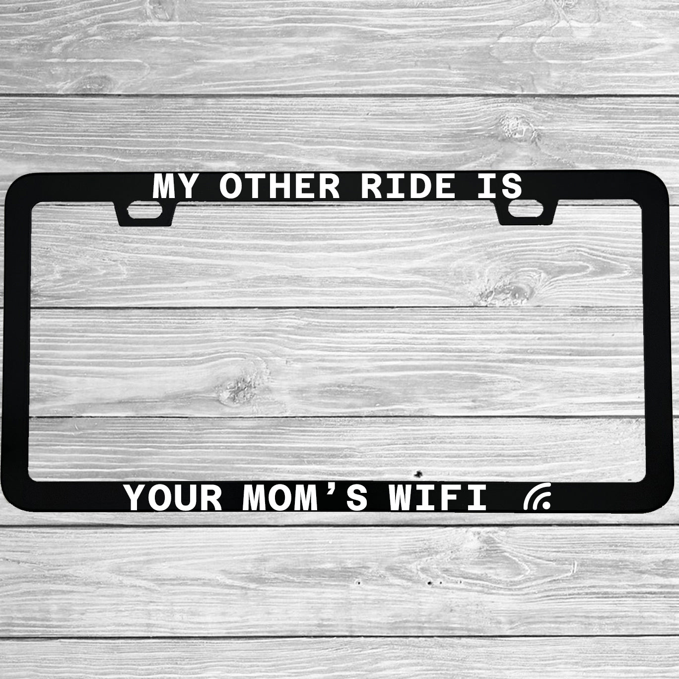 Close-up of "My Other Ride Is Your Mom's Wifi" license plate frame showing fade-proof print quality