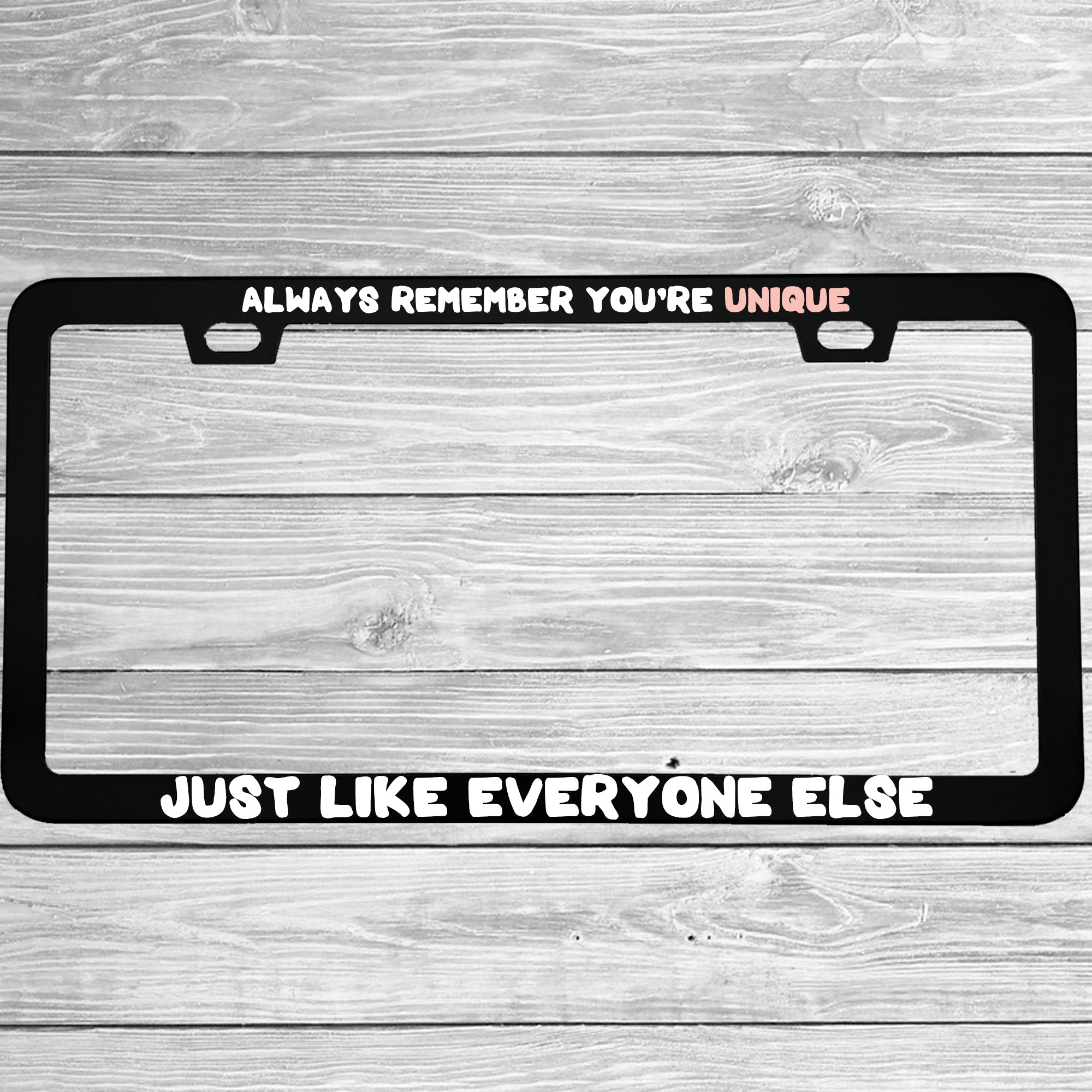 Close-up of "Always Remember You're Unique Just Like Everyone Else" license plate frame showing fade-proof print quality