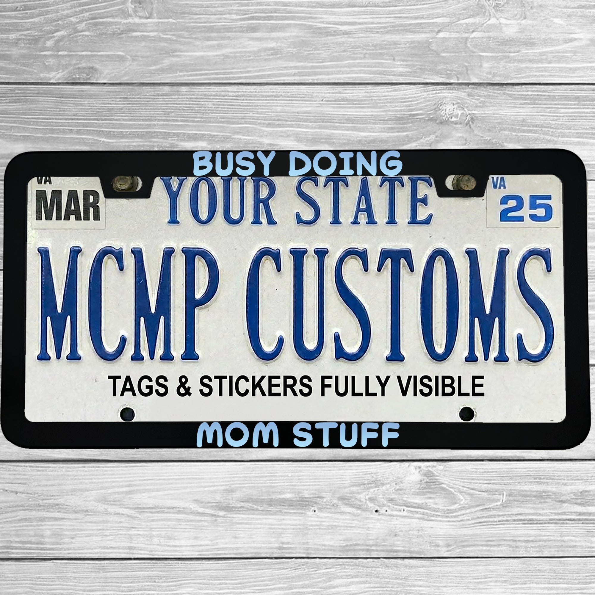 "Busy Doing Mom Stuff" license plate frame shown on vehicle — lifestyle photo
