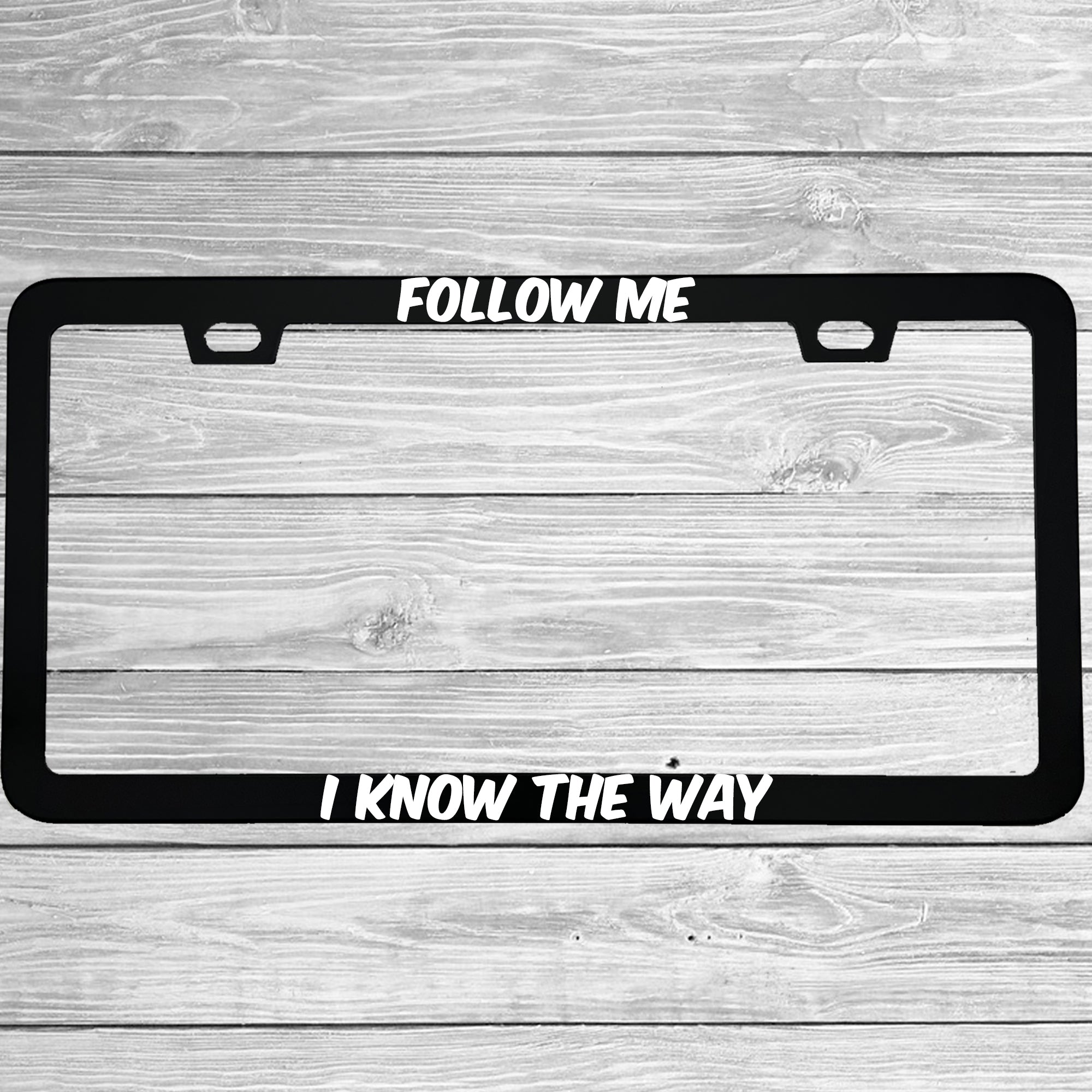 Close-up of "Follow Me I Know The Way" license plate frame showing fade-proof print quality