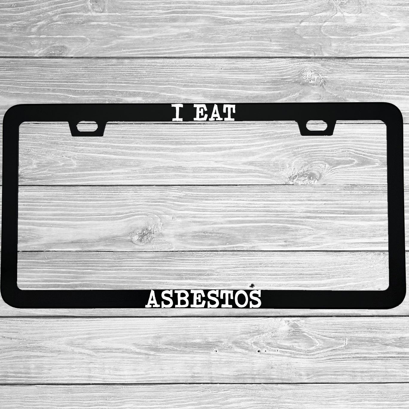 Close-up of "I Eat Asbestos" license plate frame showing fade-proof print quality