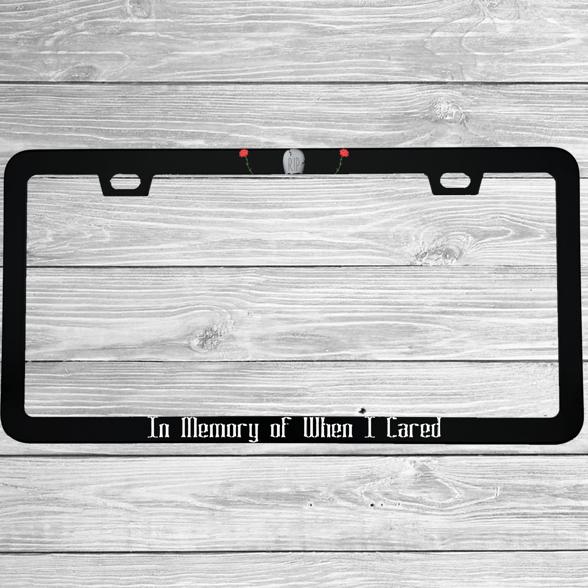 Close-up of "In Memory Of When I Cared" license plate frame showing fade-proof print quality