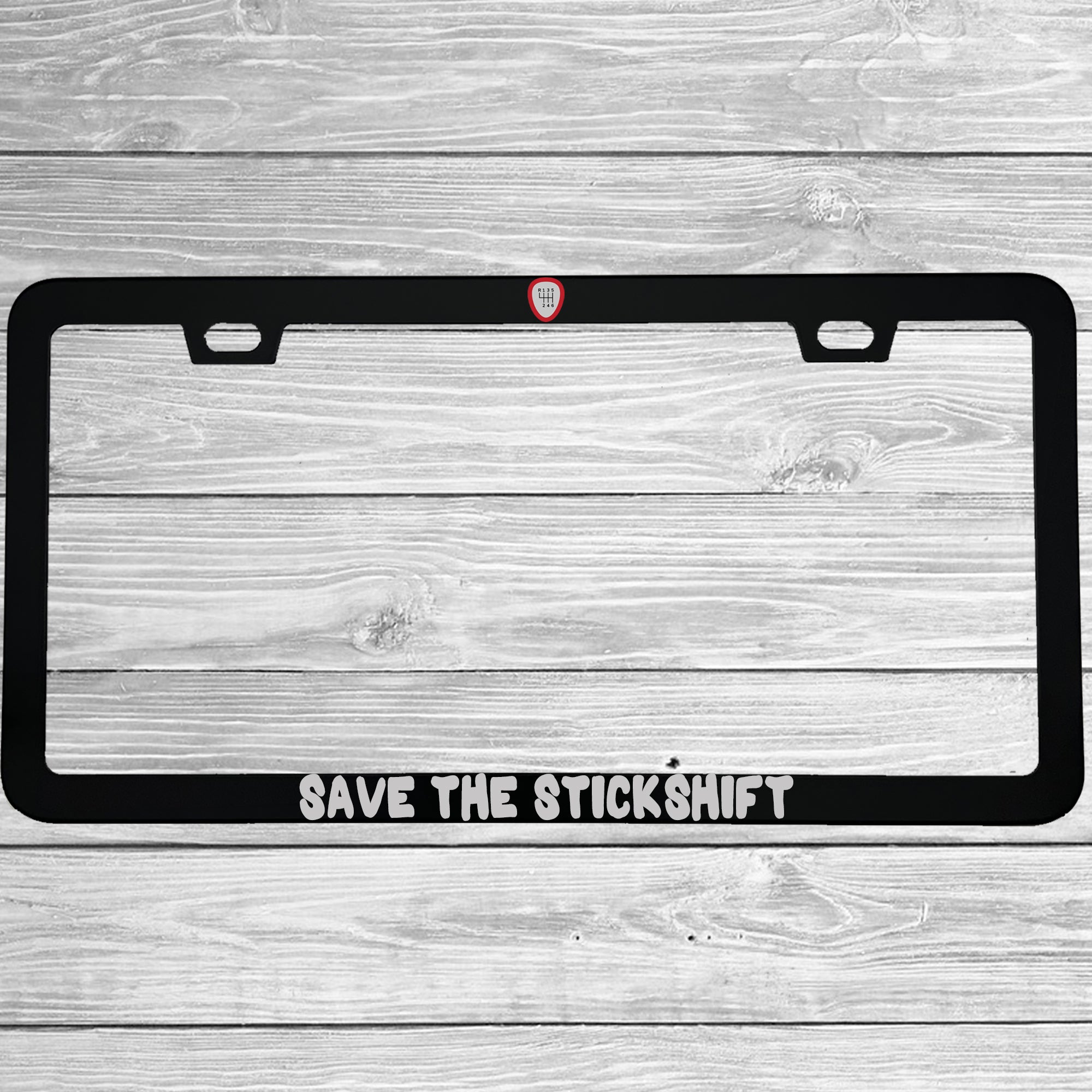 Close-up of "Save The Stickshift Manual Driving" license plate frame showing fade-proof print quality