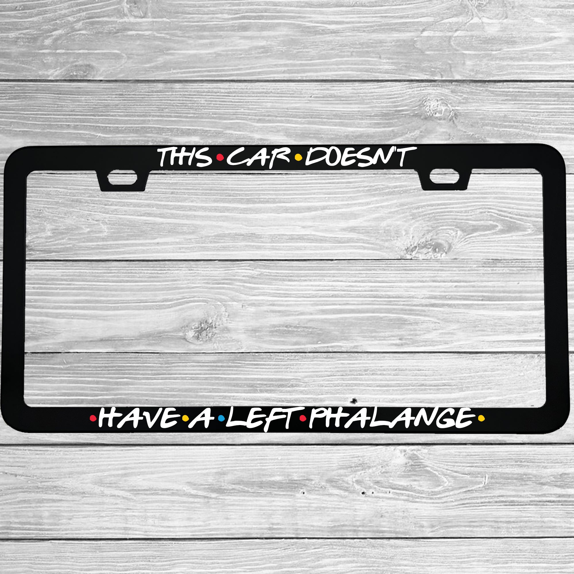 Close-up of "This Car Doesn't Have A Left Phalange" license plate frame showing fade-proof print quality