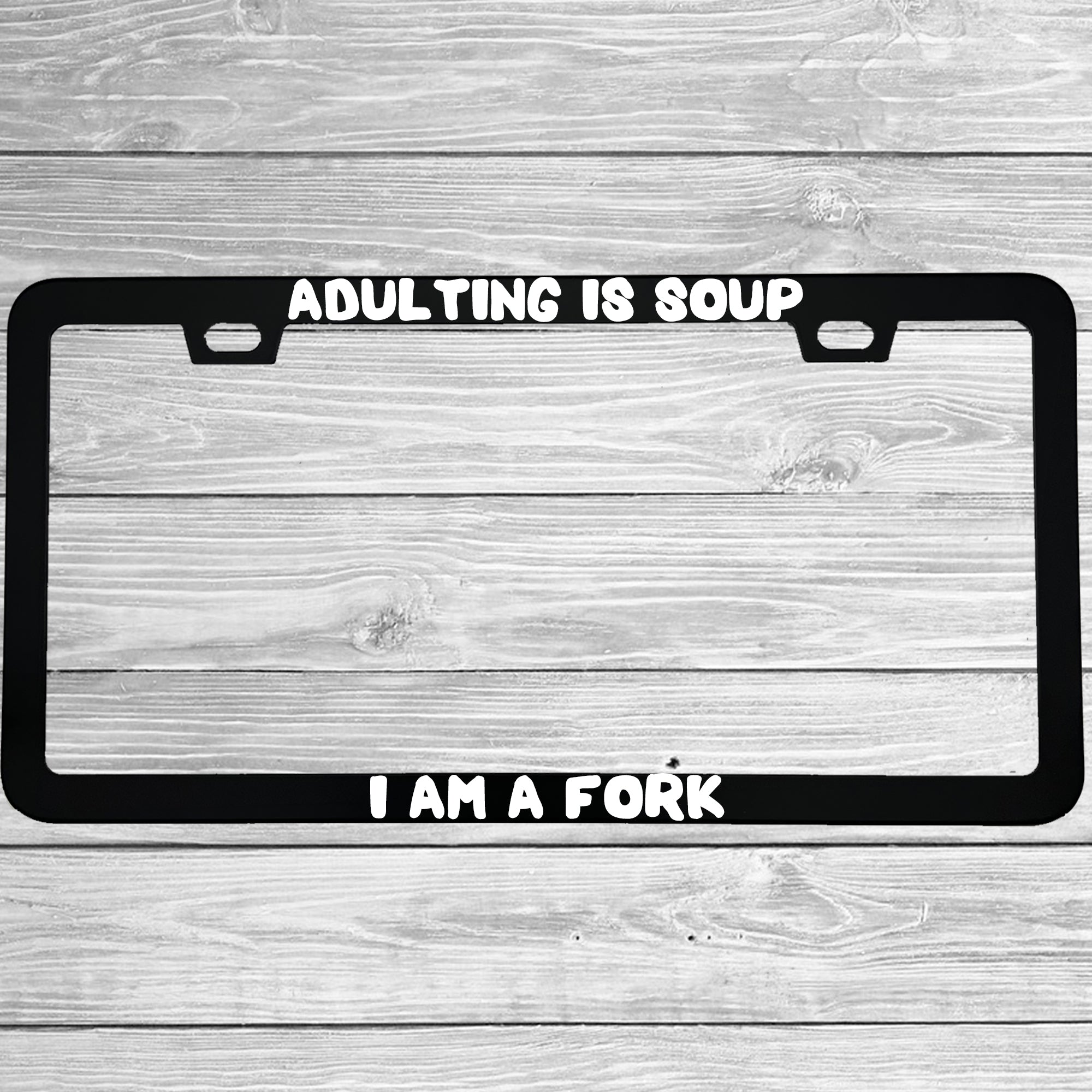 Close-up of "Adulting Is Soup, I Am A Fork" license plate frame showing fade-proof print quality
