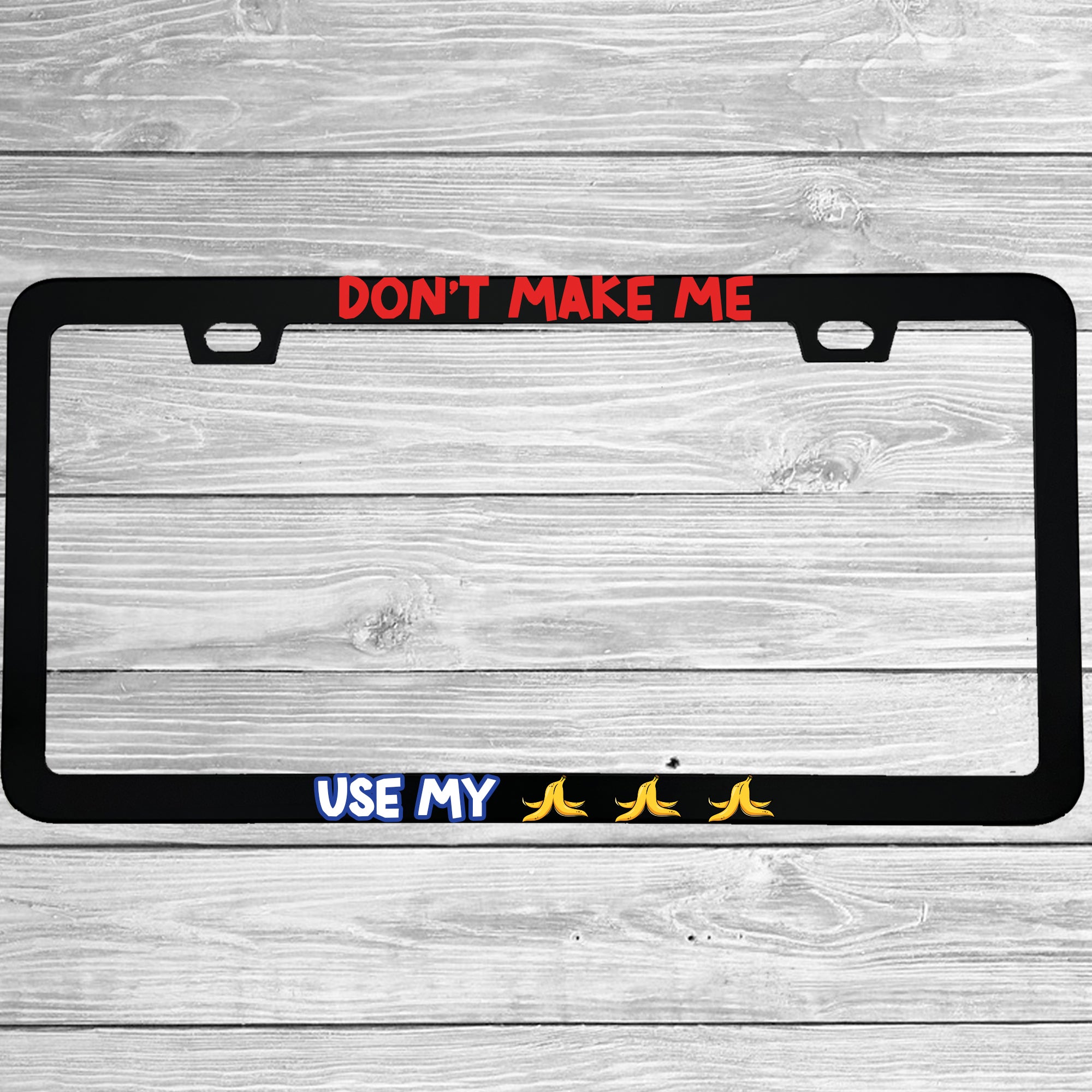 Close-up of "Don't Make Me Use My Bananas Funny Gaming Cartoon" license plate frame showing fade-proof print quality