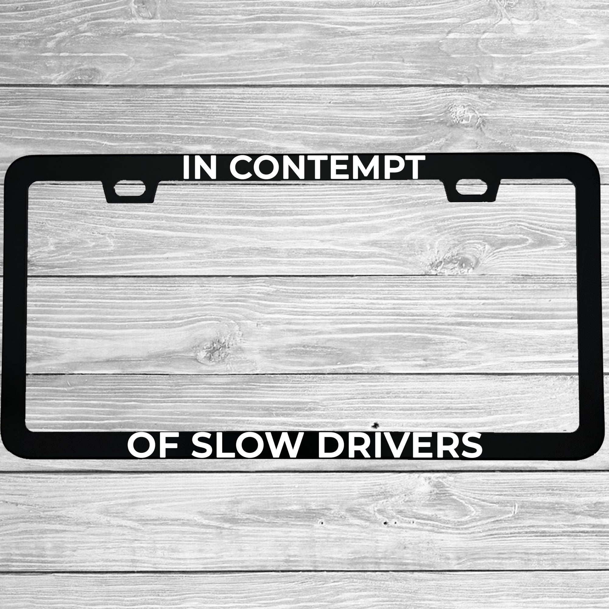 Close-up of "In Contempt of Slow Drivers" license plate frame showing fade-proof print quality
