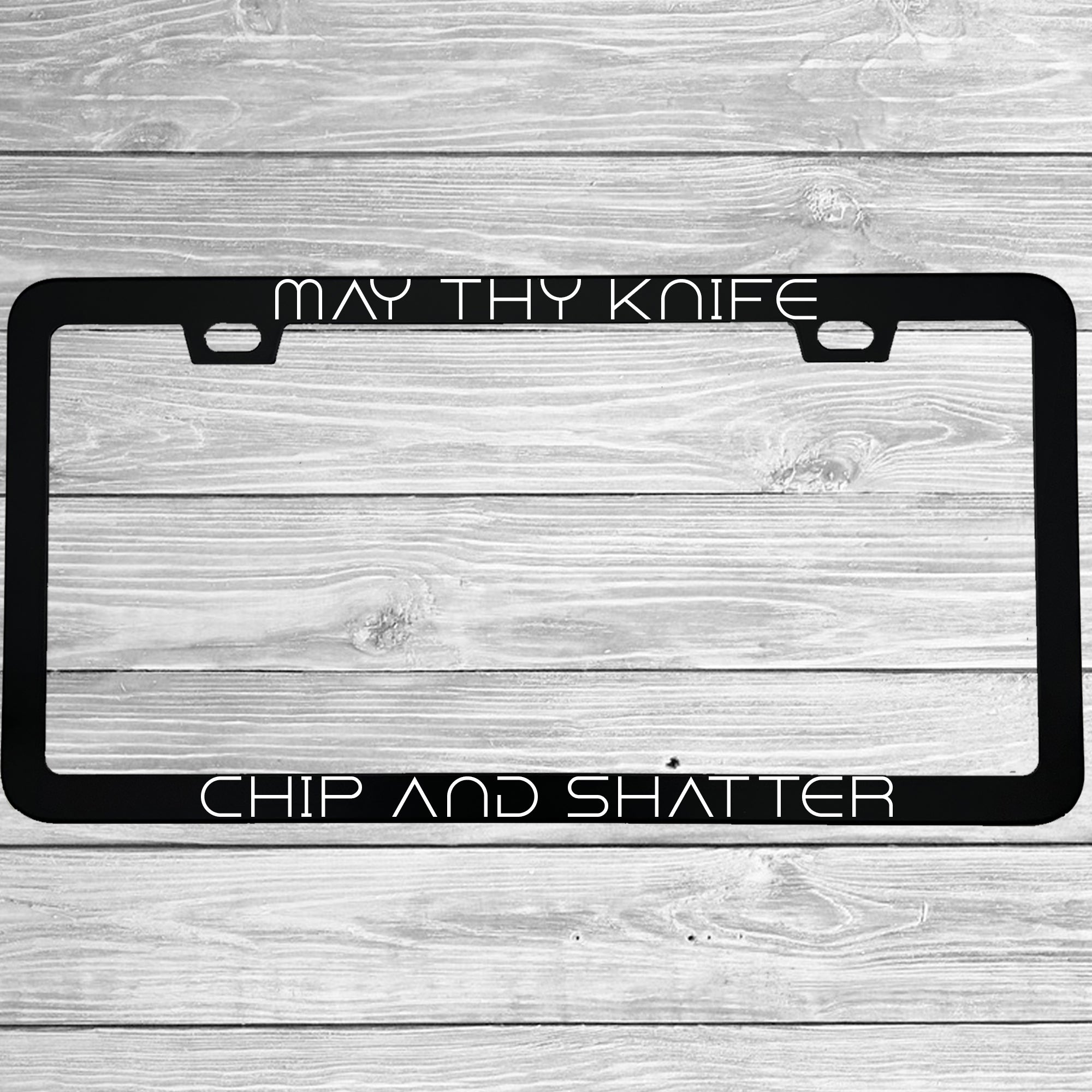 Close-up of "May Thy Knife Chip and Shatter" license plate frame showing fade-proof print quality