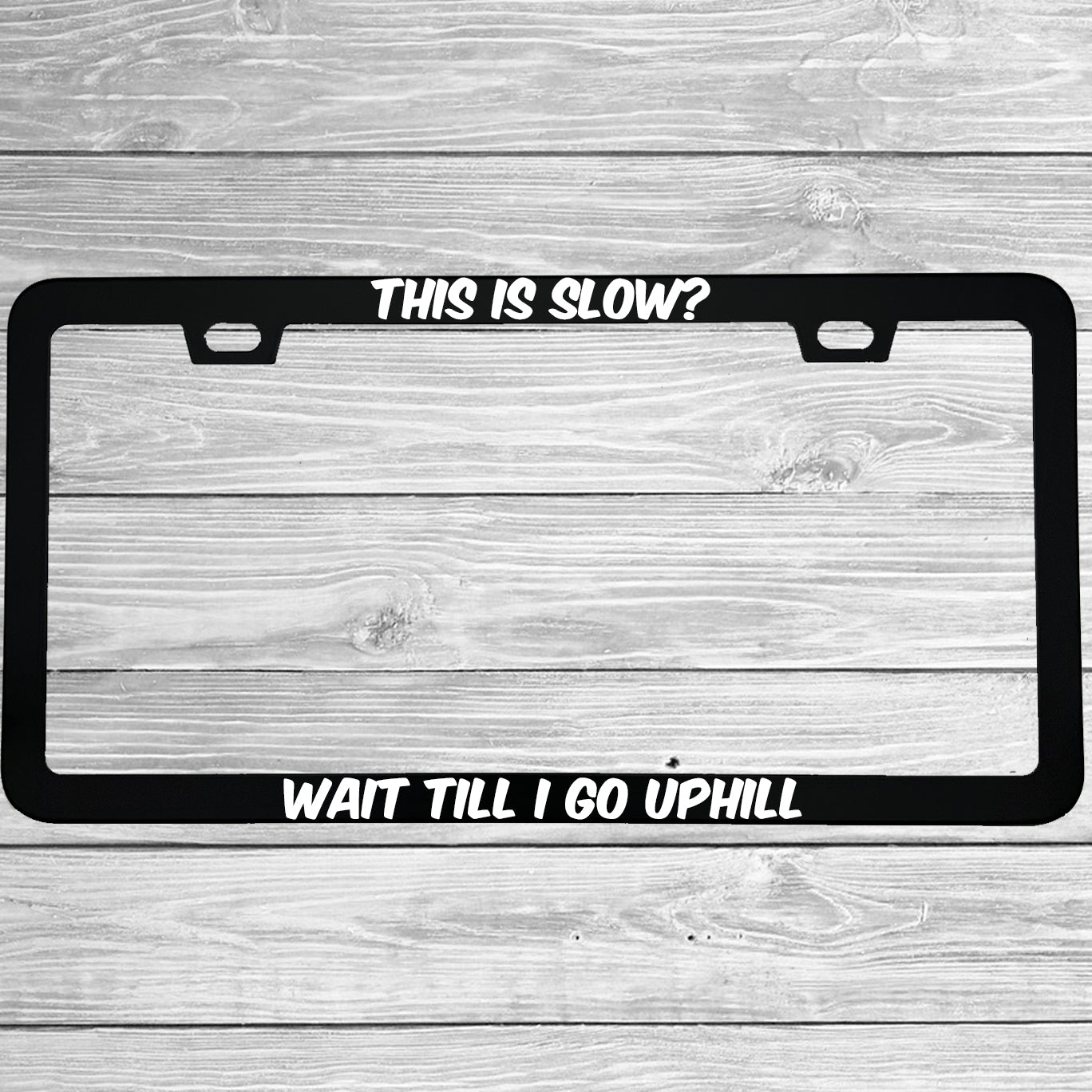 Close-up of "This Is Slow Wait Till I Go Uphill" license plate frame showing fade-proof print quality
