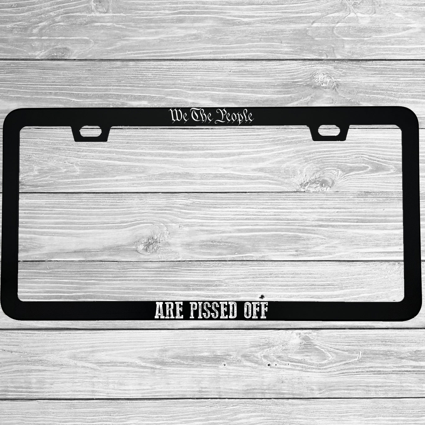 Close-up of "We The People Are Pissed Off" license plate frame showing fade-proof print quality