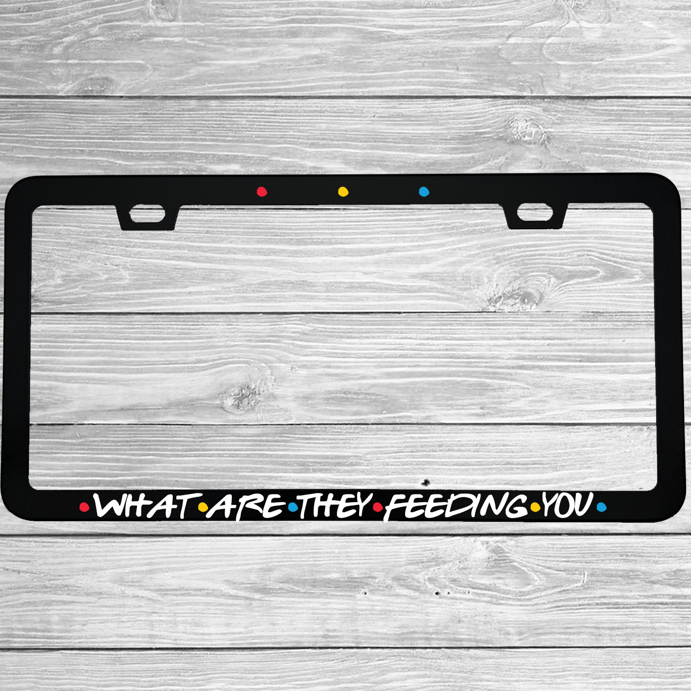 Close-up of "What Are They Feeding You" license plate frame showing fade-proof print quality